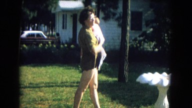 1967: a mother talking and lulling her baby in the garden in a sunny day NEVADA