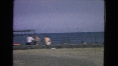 1967: people on a beach with ocean and pier behind them