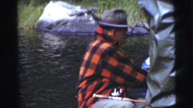 1967: Old Man in Plaid Shirt and Hat Fishing on Boat Showing Catch