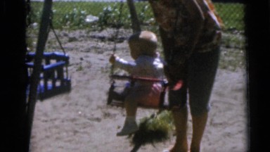 1967: three children playing on a swing set with one adult CAMDEN, NEW JERSEY