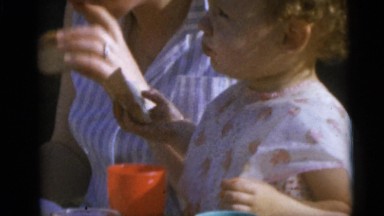 1967: beautiful babies being fed by their mothers on a sunny day outdoors.