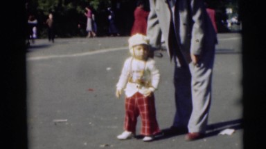 1954: a man in a suit adjusting a small boy's outfit in the street PENNINGTON,