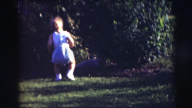 1967: child playing in the garden while her mother carries her sibling CAMDEN,