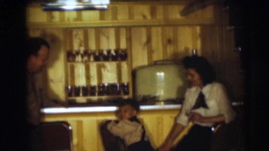 1954: a small boy climbing up on a bar stool as his parent look on PENNINGTON,