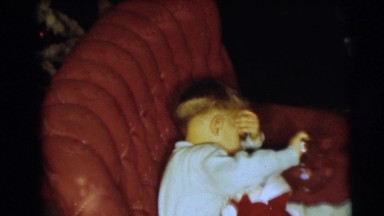 1954: a small boy in a chair opening a christmas present PENNINGTON, NEW JERSEY