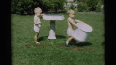 1967: two children playing with a hose and a basin in the garden CAMDEN