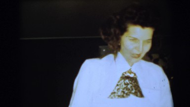 1967: Woman Walking Through Christmas-Decorated Room and Sitting in Chair, Camden, New Jersey
