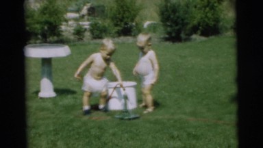 1967: two little lads playing with water coming through the hose CAMDEN
