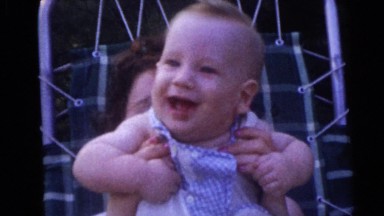 1954: A Woman Holding a Sweet Smiling Baby in Her Hands in Front of Her