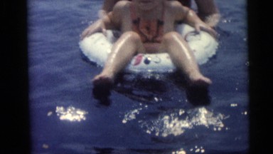 1967: a sweet little girl and boy on white plastic floats in the pool CAMDEN,
