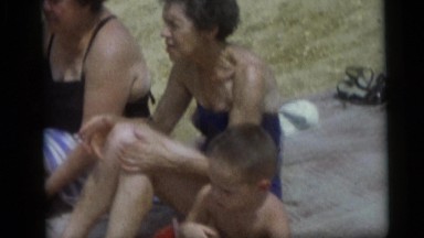 1967: Elderly Women in Bathing Suits Sitting on a Large Towel at Beach
