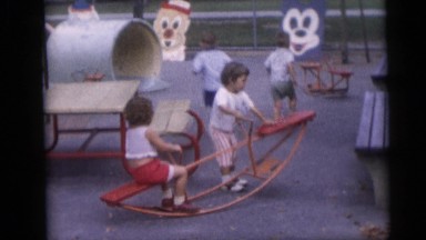 1967: Several Young Children Playing on Toys and Rides at Amusement Park