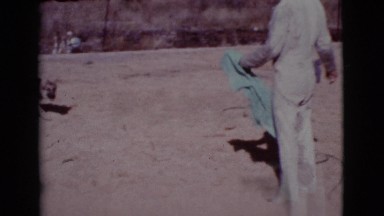 1968: a man with a blue towel outside playing with a dog COTTONWOOD, ARIZONA