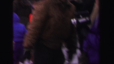 1972: a child smiles in front of a crowd of children and adults holding sleds
