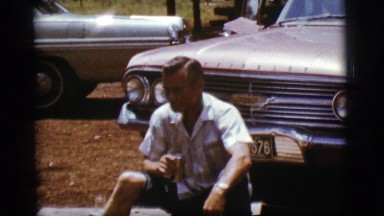 1968: man sitting outside in front of car, drink in hand COTTONWOOD, ARIZONA