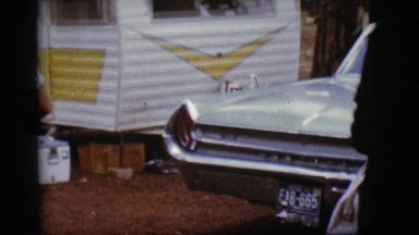 1968: a couple outside walking past a car towards a recreational vehicle