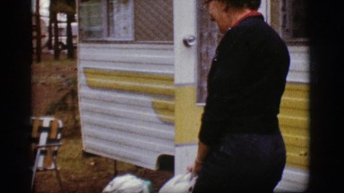 1968: a middle age woman at a camping lot goes into her 1950's camping trailer.