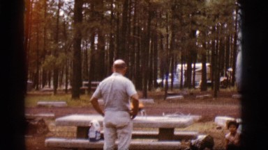 1968: man in woods at campsite with fire barbecue with children COTTONWOOD,