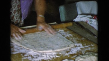 1968: a woman with a wooden dowel is shaping dough for making bread