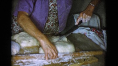 1968: a woman is using a big knife to cut a big portion of fresh dough
