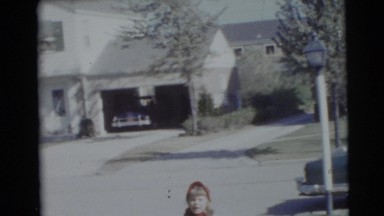 1953: young children play tugging game in yard and fall over near parked car