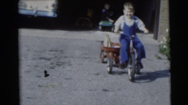 1953: the big brother riding a tricycle with a load in his back