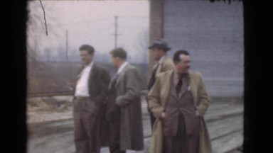 1939: 11 men standing outside in the snow next to a railroad talking. LOS