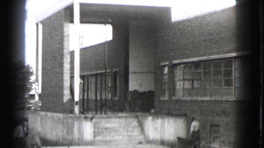 1939: Two Adult Men Working Labor Job During Daytime Near Building