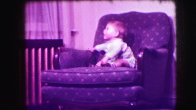 1942: retro home video of child in sofa chair looking around LOS ANGELES