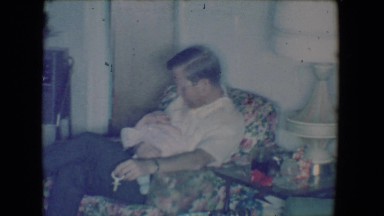 1961: Man in Chair Holding Baby at Salton Sea, California