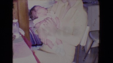 1961: Mom Comforting Young Baby While Dad Washes Dishes in Kitchen