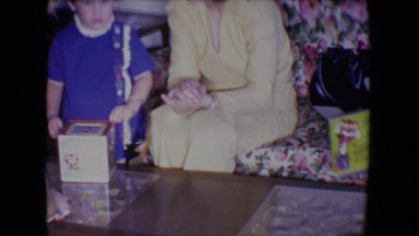 1961: child receiving gifts and playing with jack in box with family watching
