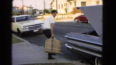 1966: man lifts box into trunk SAN PEDRO, CALIFORNIA