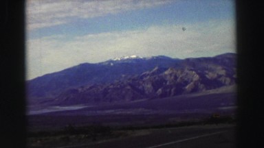 1969: a man standing near a vehicle with a beautiful mountain in the background