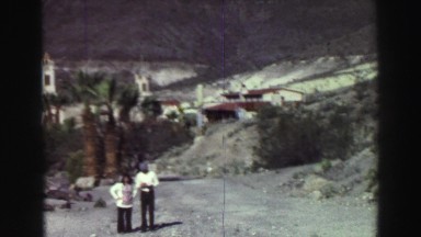 1969: couple standing outside village in rocky desert with palm trees YOSEMITE,