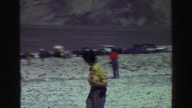 1969: people stand on salt flat below mountain next to cars YOSEMITE, CALIFORNIA