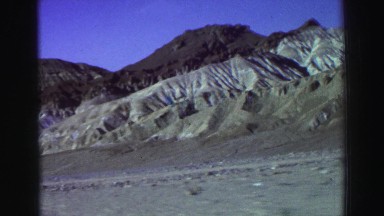 1969: a car driving down a rural desert road near foothills. YOSEMITE,