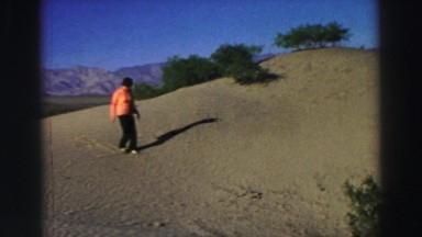 1969: a woman in orange hiking across a sandy dune mountain YOSEMITE, CALIFORNIA