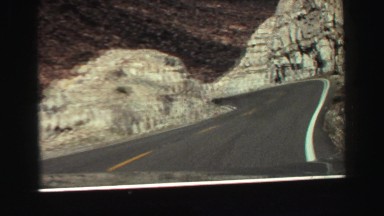 1969: car slowly drives up winding mountain road YOSEMITE, CALIFORNIA