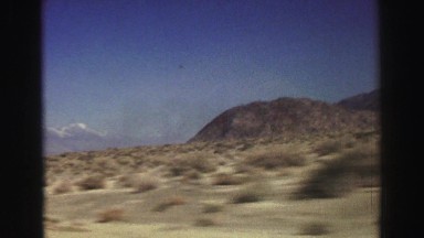 1969: Driving Through a Dry Desert with Patches of Grass and a Small Mountain