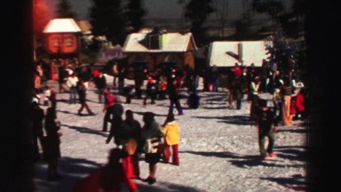 1969: hundreds of people in colorful clothing are gathered at a village resort.