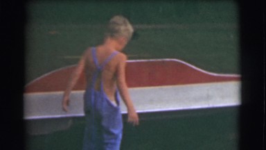 1951: young boy playing in yard by a red table CANADA