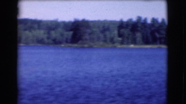 1951: a motorboat travelling across a beautiful blue lake in the wilderness