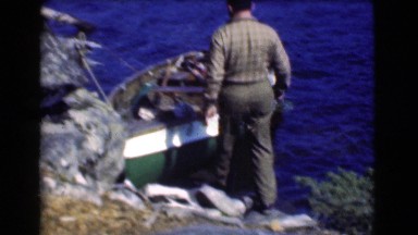 1951: a man climbing in a small boat anchored to the shoreline CANADA