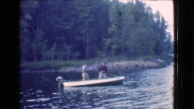 1951: two men fishing in a boat in the lake surrounded by trees CANADA