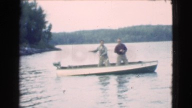 1951: two men fishing together on motorboat capture a fish with teamwork CANADA