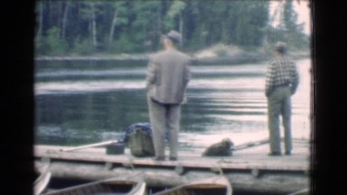 1951: a group of four men on the dock of a quiet lake looking at a seaplane