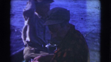 1951: two male friends wearing hats explore the ocean in a motorboat CANADA