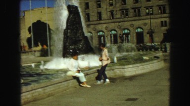 1968: Two Women Sitting Near Fountain Waving at Camera in Vancouver, Canada