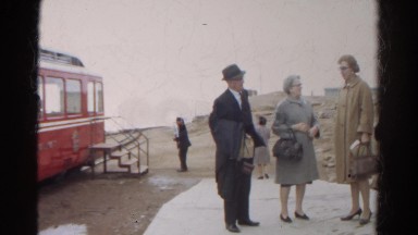 1967: vacationing people talking and waiting to board large red tour bus
